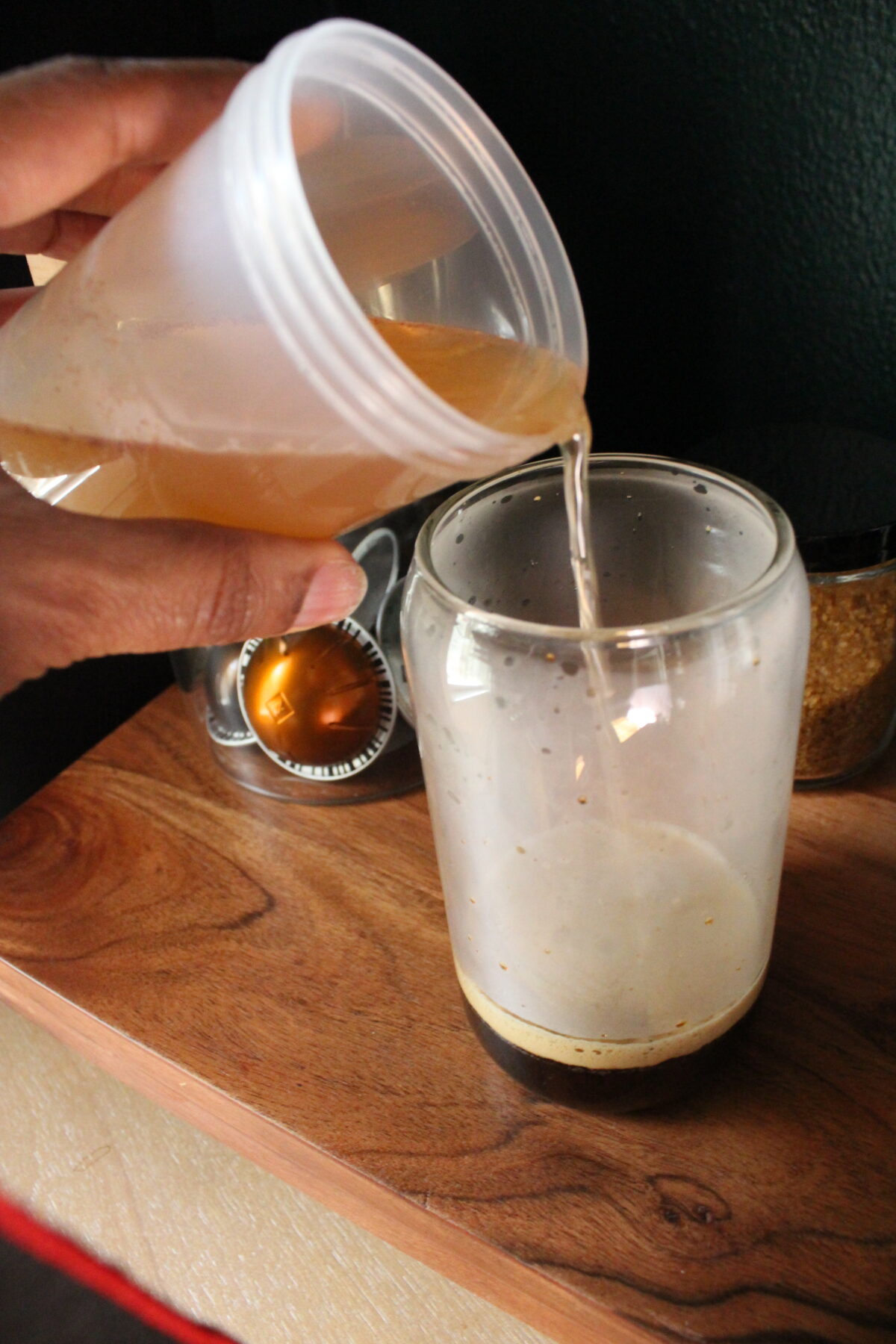 Photo of hand pouring simple syrup into espresso.